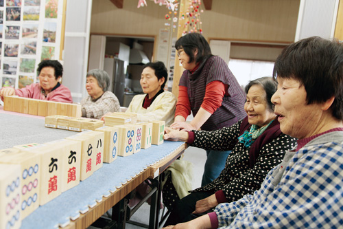 体も動かせる巨大な牌で、麻雀を楽しむ飯舘村の避難者。中央が長谷川さん＝伊達市の仮設住宅