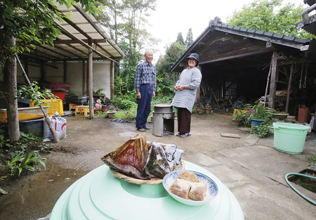 あくまきを煮込む釜戸の前にて。下八重光子さんと夫の一郎さん