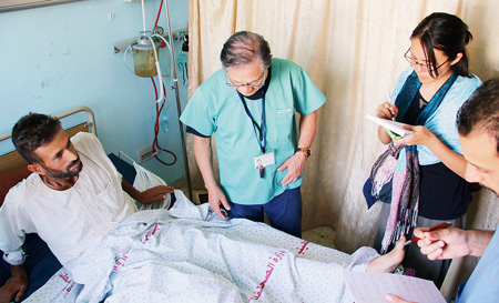 治療にあたる猫塚医師（中央）と聞き取りを行うJVCの山村さん（右）
