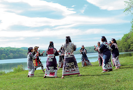 ポロト湖の湖畔で伝統舞踊を舞う人たち（公益財団法人アイヌ民族文化財団提供）