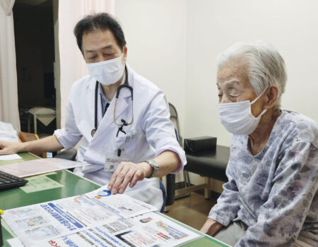 診察室で患者に署名の説明をする赤路所長